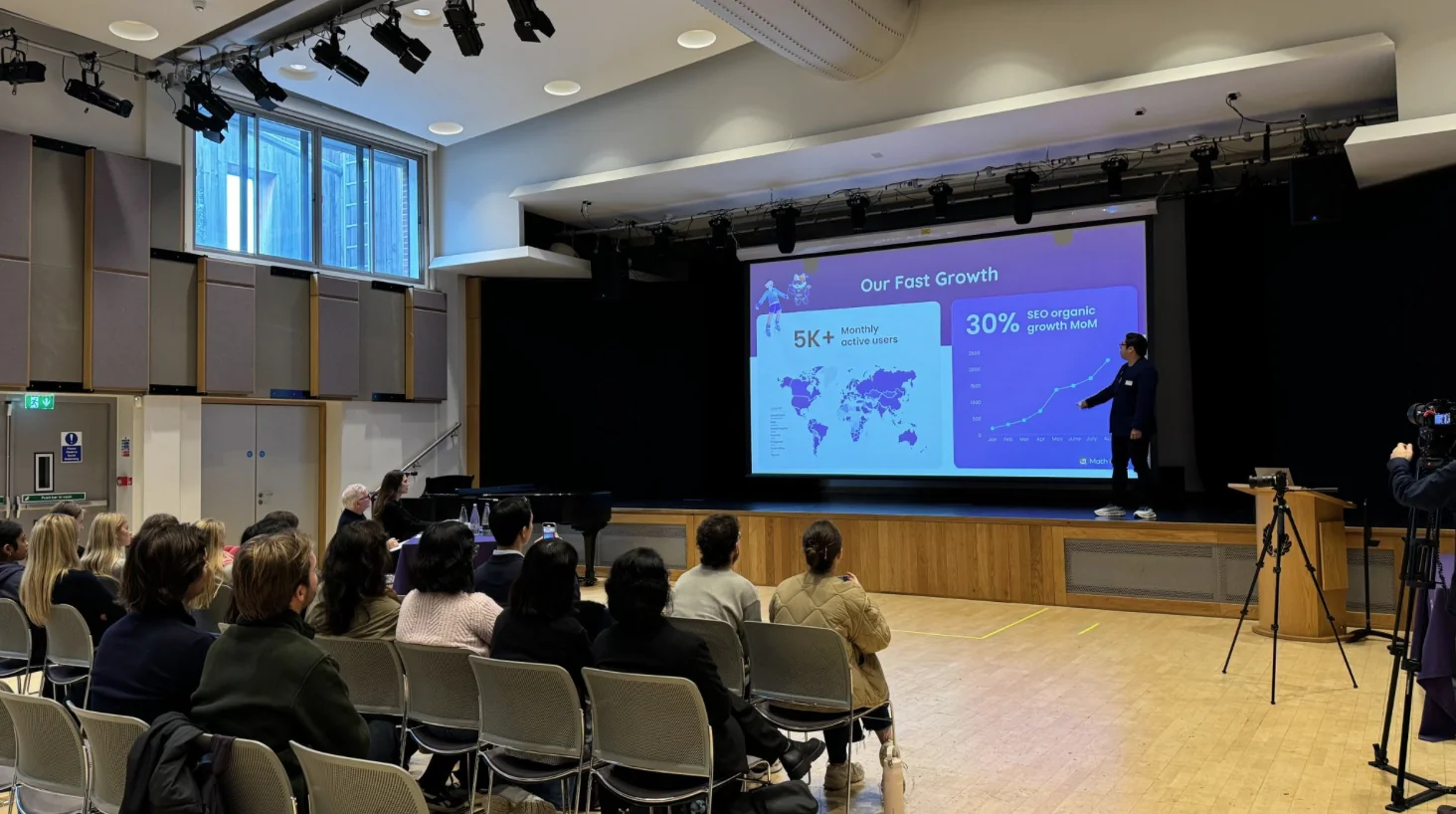 Maths Angel co-founder An-Nam pitching the AI maths tutor on the Live Stage at the LSE Generate Startup Competition 2025, with a company growth slide on screen and the audience seated.