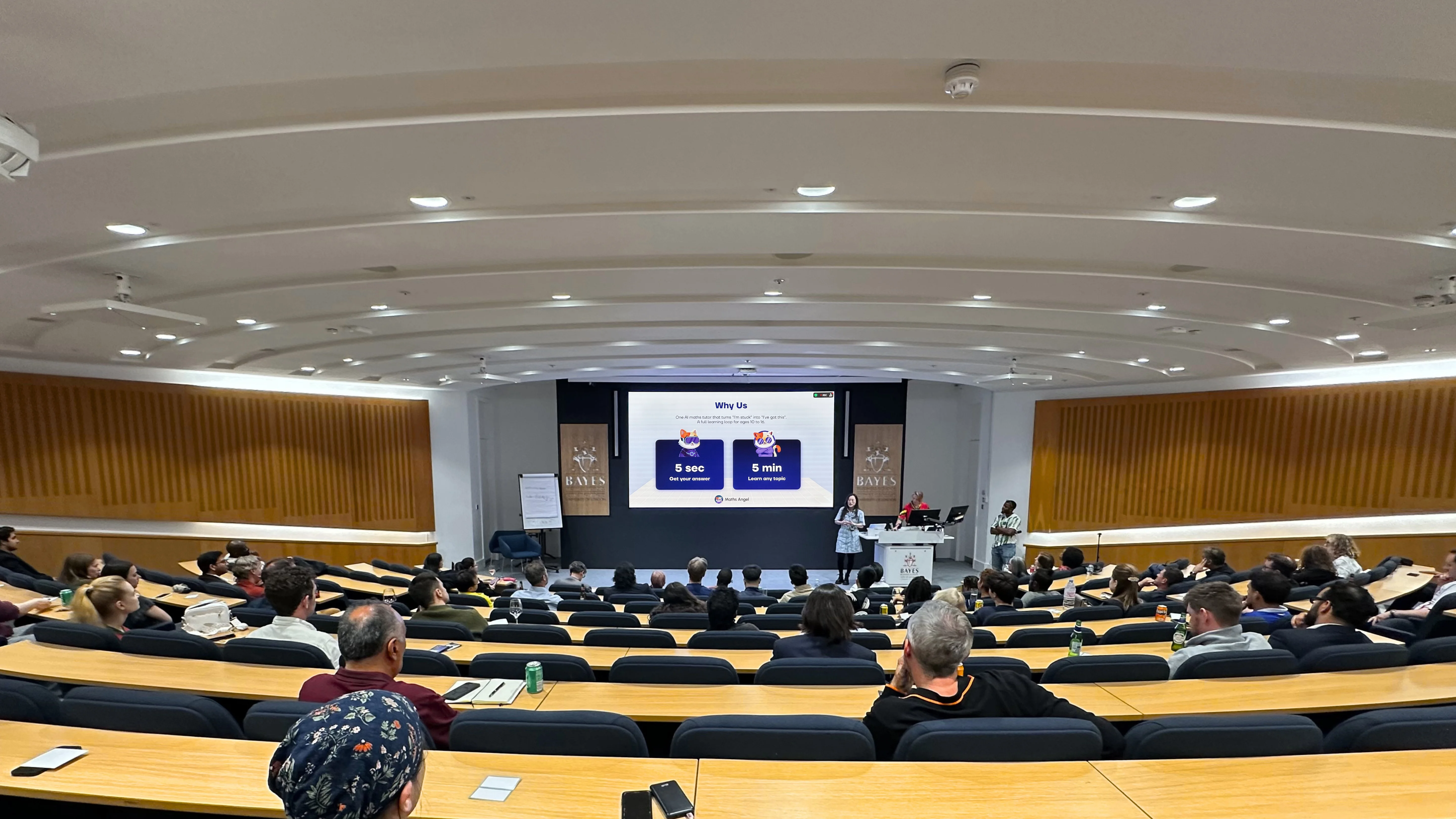 Maths Angel co-founder Lexie Li pitching the AI maths tutor on stage to a seated audience at Canopy Community's Demo Night during London Tech Week 2026, with a five-second, five-minute slide on screen.